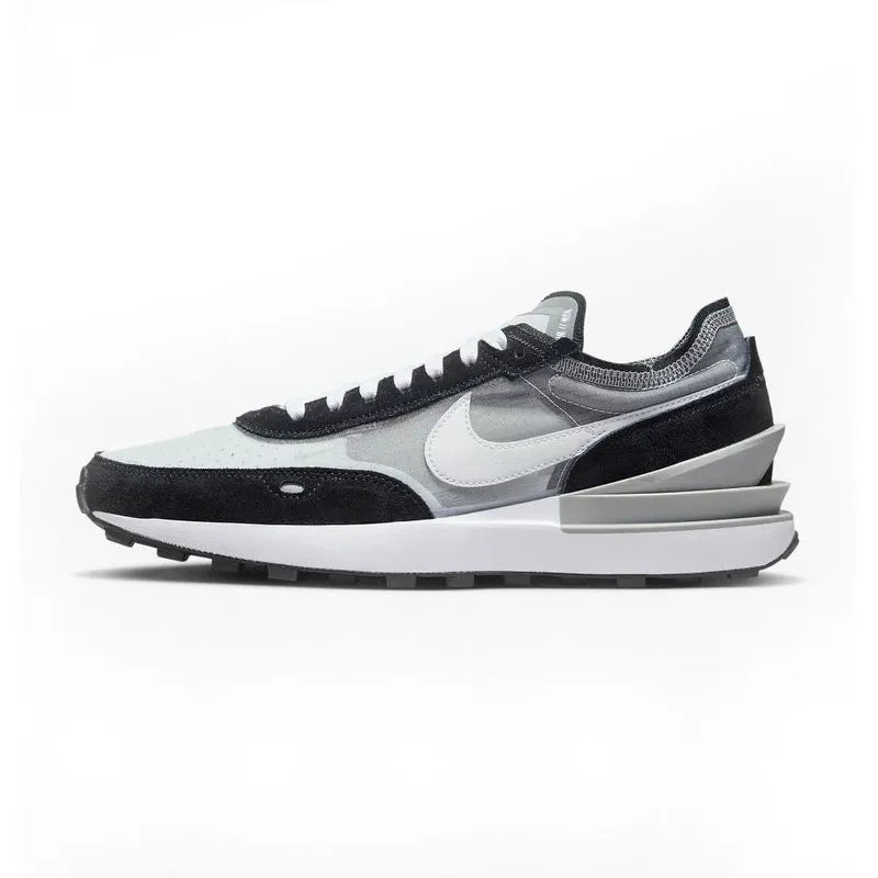 A pair of Nike Waffle One sneakers with a black and white color scheme, featuring a waffle-inspired outsole and a cushioned midsole.