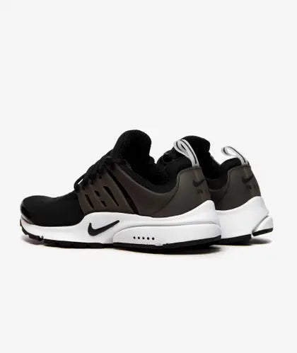 A pair of black and white Nike Air Presto sneakers with visible mesh upper, cushioning technology, and rubber outsole.