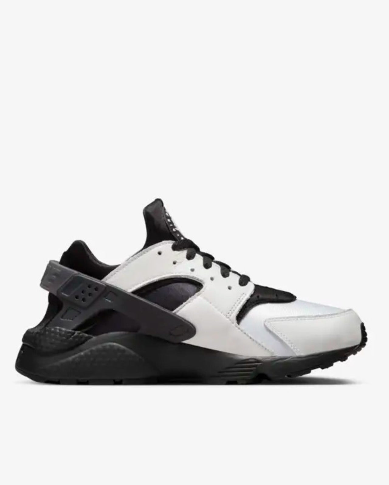 A pair of Nike Air Huarache sneakers with a white and black neoprene bootie, white leather overlays, and a black heel clip on a solid black rubber sole.