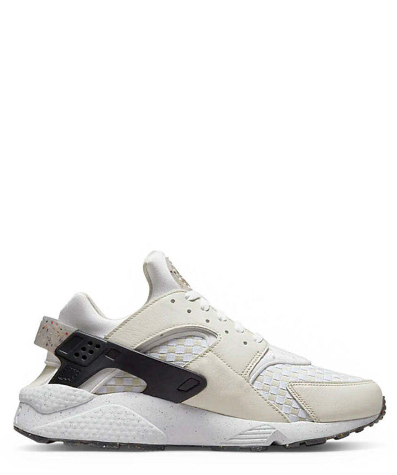 Nike Air Huarache sneaker in white and beige color with neoprene details, leather overlays, and a green-speckled midsole.