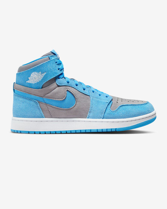 A pair of Air Jordan 1 Zoom CMFT sneakers in Cement Grey, University Blue, and White color blocking with a visible White Wings logo on the lateral ankle.