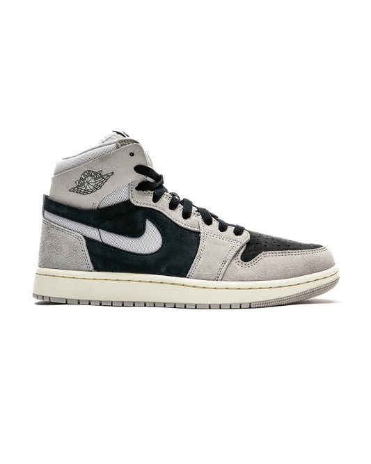 High-top Air Jordan 1 Zoom CMFT 2 sneakers with light iron ore, neutral grey, black, and coconut milk color scheme, featuring soft suede and mesh materials, iconic cut-out Swooshes, and 'Zoom Air' branding on the tongue.